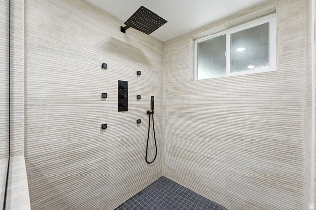 871 Bonita Way Centerville, UT 84014 - Photo 31 of 61 Spacious shower featuring textured wall tiling, matte black fixtures, a rain shower head, multiple body sprayers, and a handheld shower wand