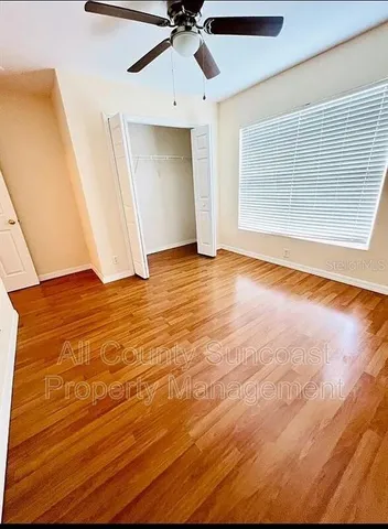 an empty room with wooden floor fan and windows