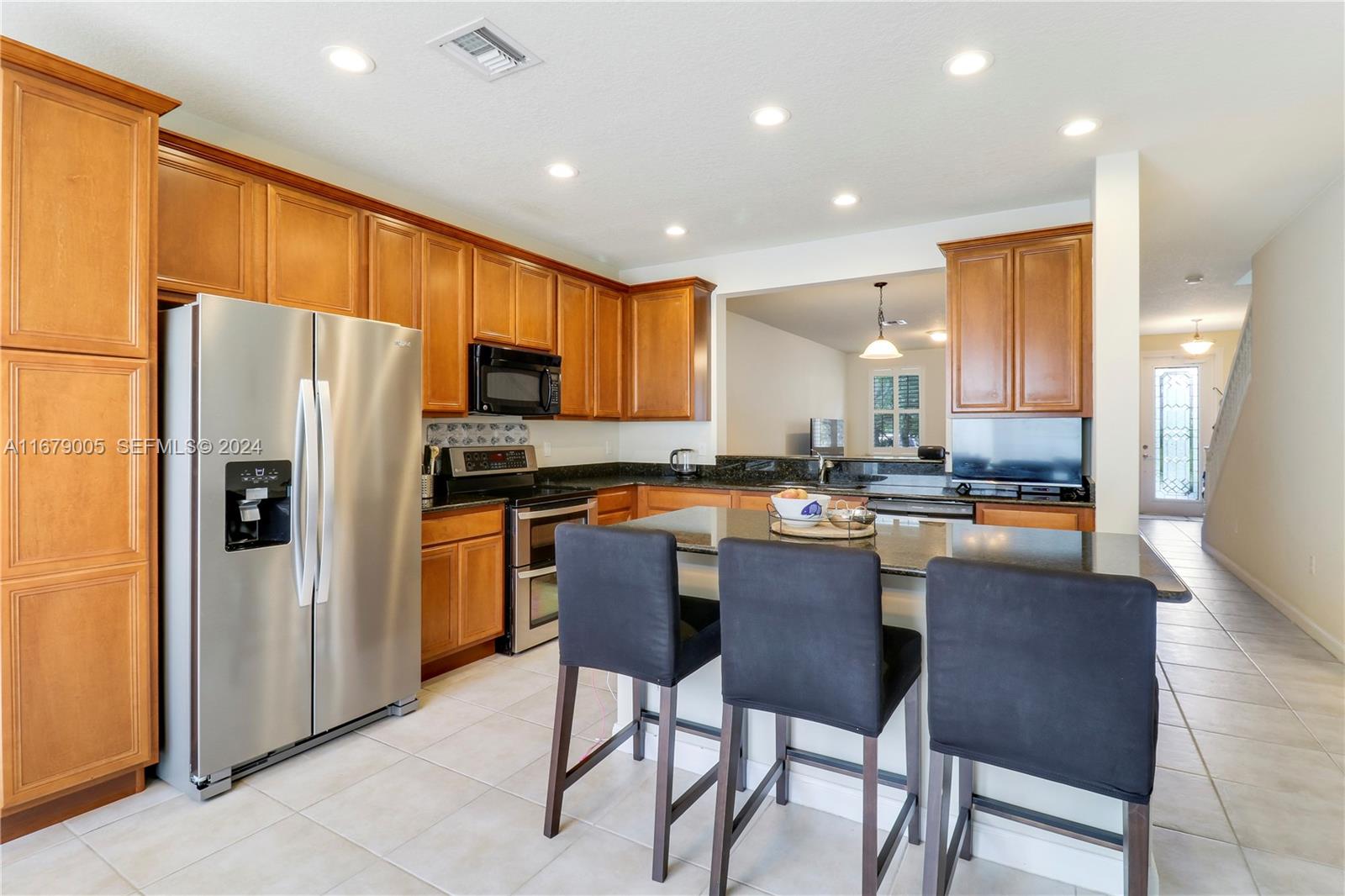 1184 Islamorada Drive, Unit 1184 Jupiter, FL 33458 - Photo 11 of 34 a kitchen with granite countertop a refrigerator a stove a sink a dining table and chairs