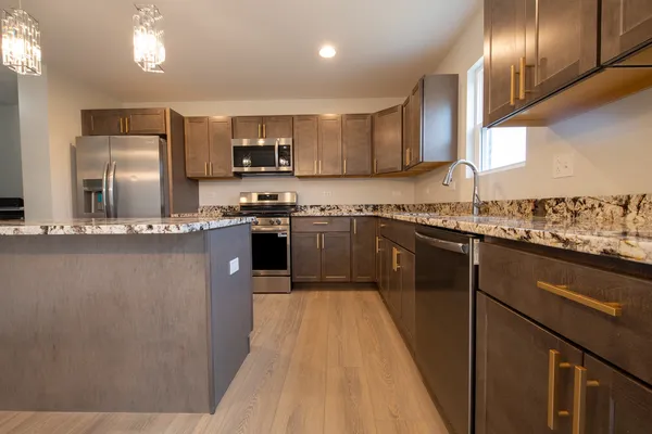 a kitchen with stainless steel appliances granite countertop a sink a stove a refrigerator and white cabinets