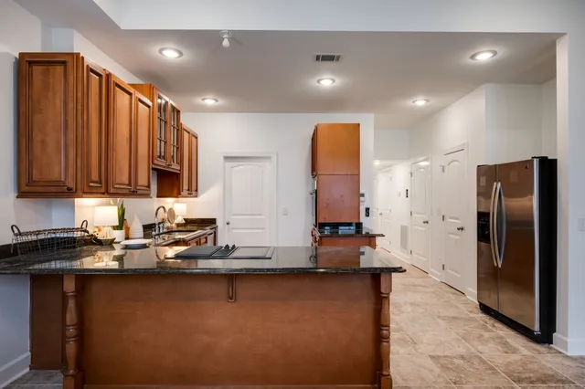 a kitchen with stainless steel appliances granite countertop a refrigerator a stove and a sink with wooden cabinets