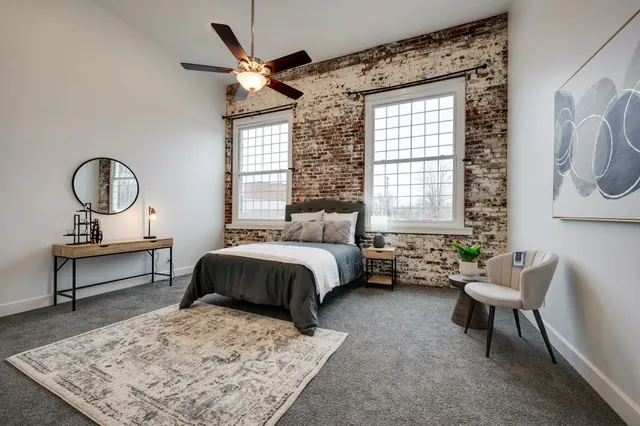 a bedroom with a bed and large windows