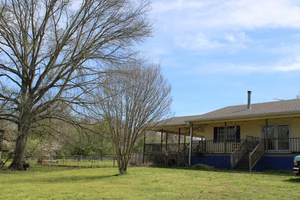 a front view of a house with a yard and large trees