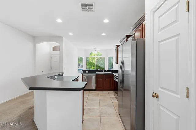 a kitchen with kitchen island granite countertop a sink and a refrigerator