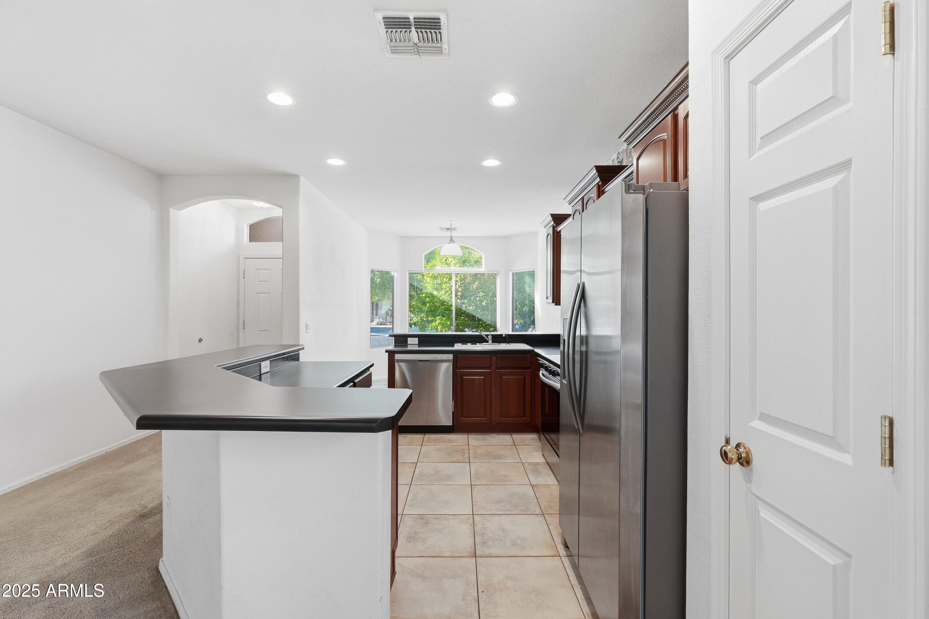 14568 West Crocus Drive Surprise, AZ 85379 - Photo 11 of 36 a kitchen with kitchen island granite countertop a sink and a refrigerator