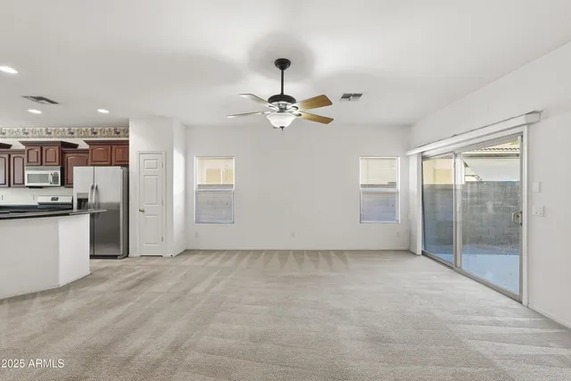 a view of an empty room with cabinet and a ceiling fan