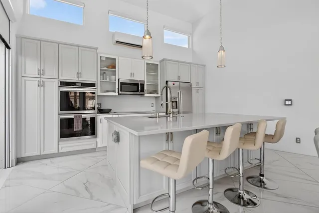 a kitchen with stainless steel appliances a table chairs microwave and refrigerator