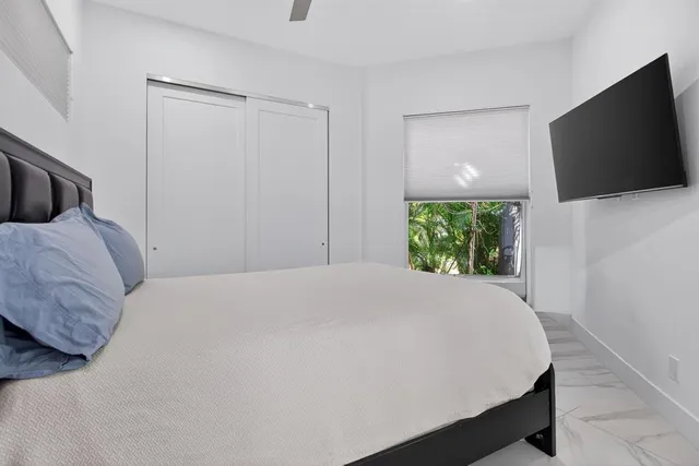 a bedroom with a bed a flat screen tv and a large window