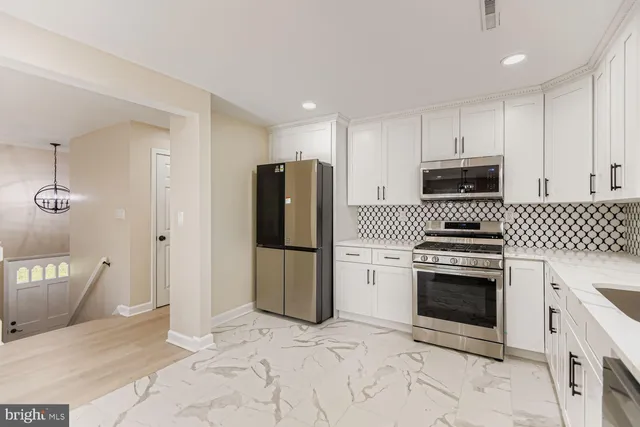 a large kitchen with stainless steel appliances kitchen island a stove a refrigerator a sink dishwasher with a dining table and chairs