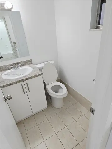 a bathroom with a granite countertop toilet and a sink