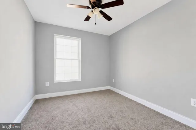 an empty room with a window and a fan