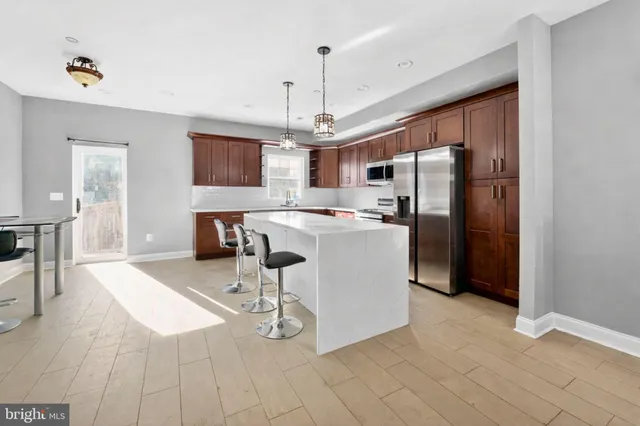 a kitchen with stainless steel appliances granite countertop a refrigerator a sink dishwasher a dining table and chairs with wooden floor