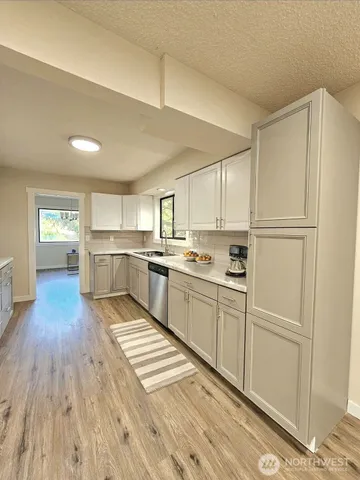 a kitchen with white cabinets and wooden floor