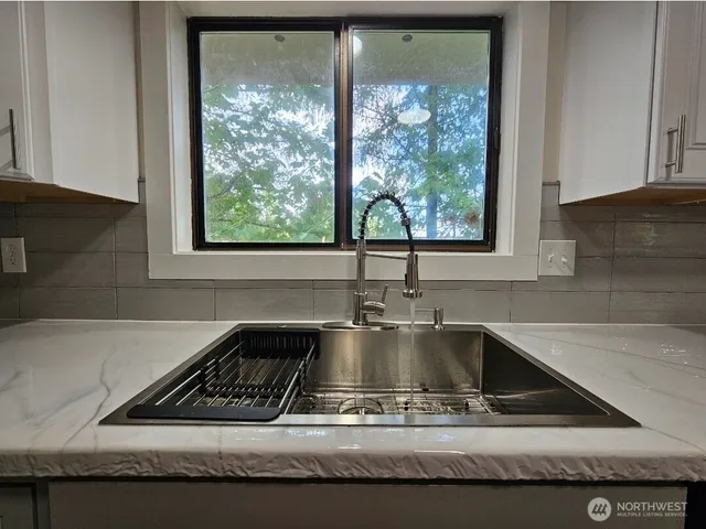 a kitchen with kitchen island granite countertop a sink a counter space and windows