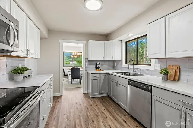 a kitchen with a sink a stove cabinets and wooden floor