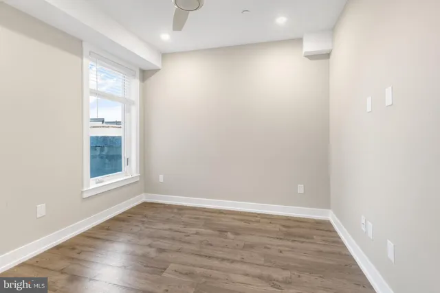 a view of an empty room with wooden floor and a window