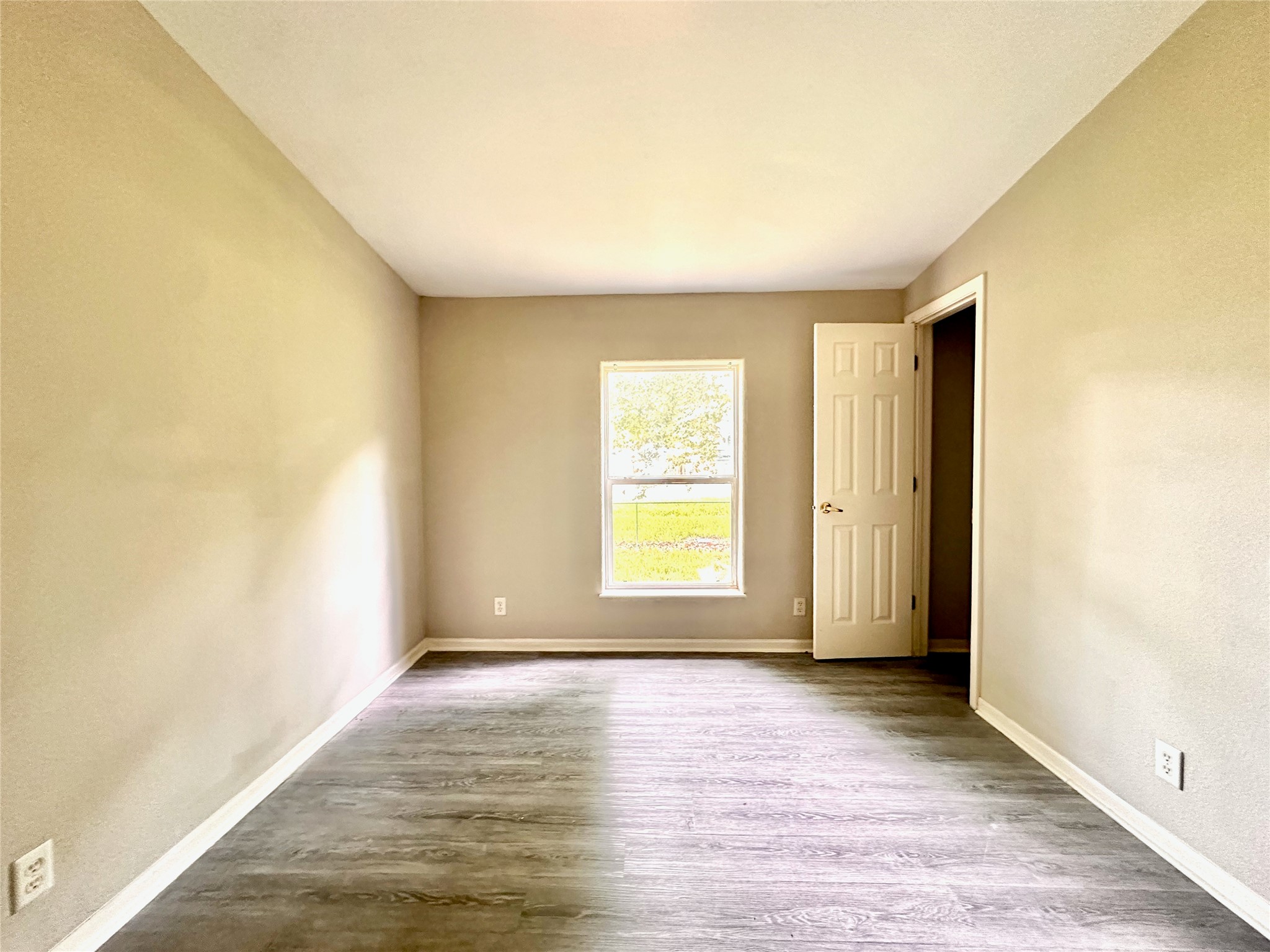 202 Main Street Fresno, TX 77545 - Photo 23 of 26 an empty room with wooden floor and windows with curtains