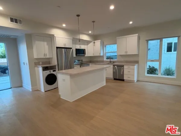 a kitchen with kitchen island a sink a stove a refrigerator cabinets and a counter top space