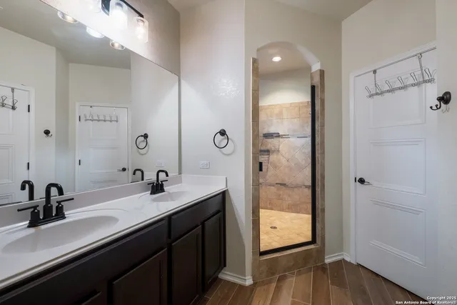 a bathroom with a double vanity sink a mirror and shower