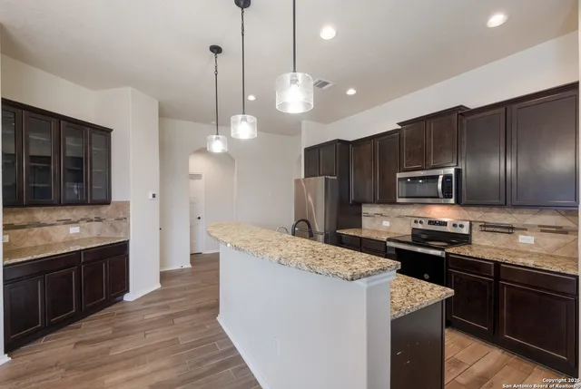 a kitchen with kitchen island granite countertop stainless steel appliances and wooden cabinets