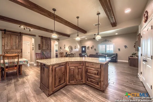 a kitchen with stainless steel appliances granite countertop wooden floors and view of living room
