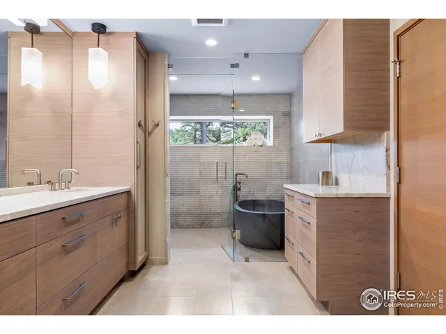 a bathroom with a double vanity sink a large mirror and shower