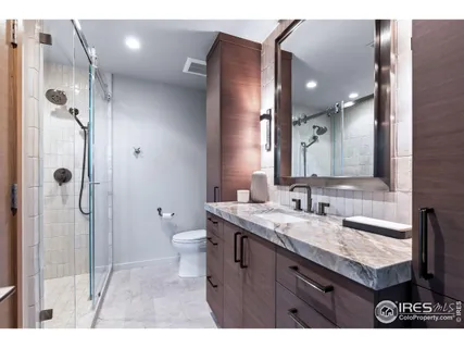 a bathroom with a granite countertop sink a toilet a mirror and shower