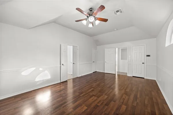 an empty room with wooden floor and a ceiling fan