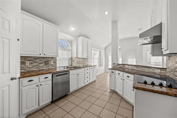 a large kitchen with granite countertop a sink and cabinets