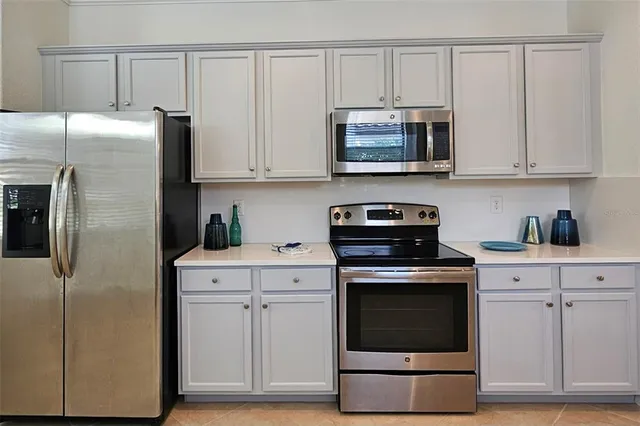 a kitchen with stainless steel appliances granite countertop white cabinets a refrigerator and a stove top oven