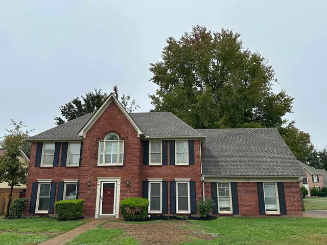 a front view of brick house with a yard