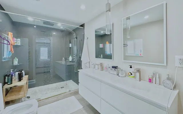 a bathroom with a sink vanity granite tub shower and mirror