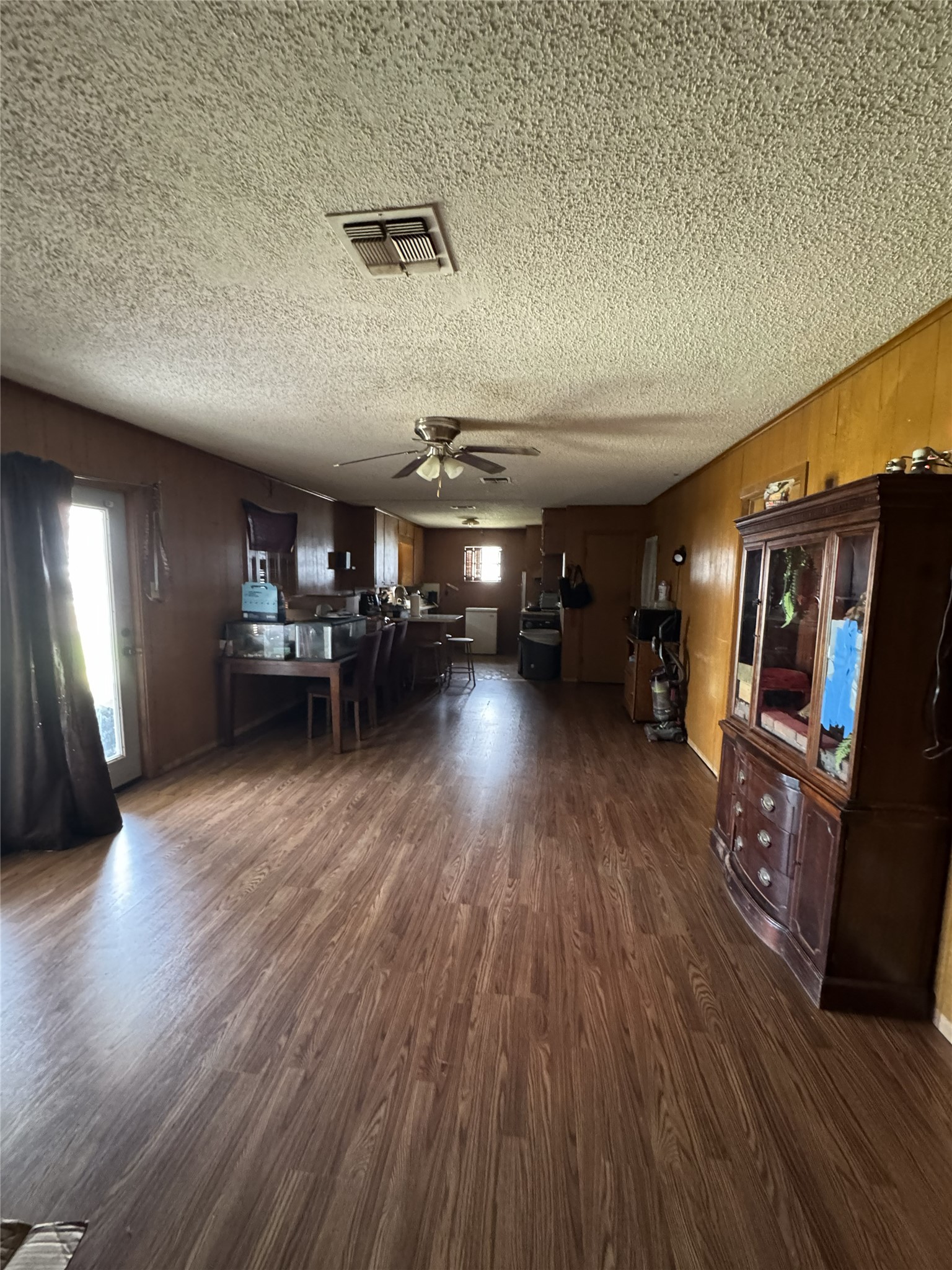 106 North 7th Street Dawson, TX 76639 - Photo 19 of 28 Living room with dark wood-style floors, ceiling fan, a textured ceiling, and wood walls