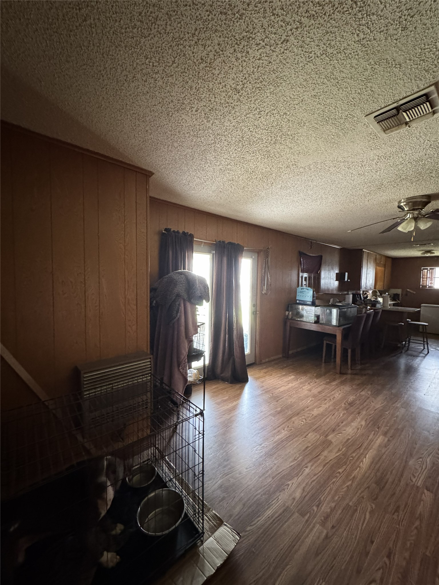 106 North 7th Street Dawson, TX 76639 - Photo 20 of 28 Dining area with ceiling fan, dark wood finished floors, wooden walls, a textured ceiling, and heating unit