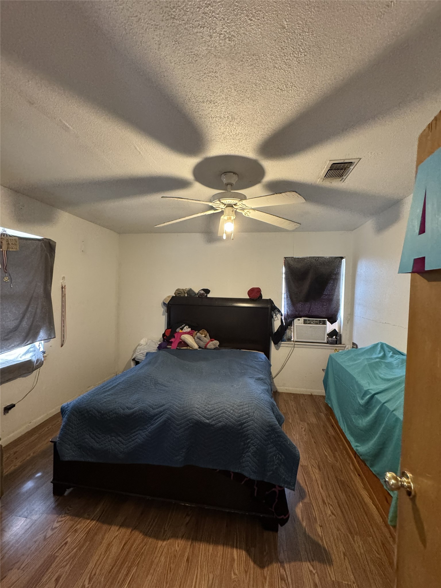 106 North 7th Street Dawson, TX 76639 - Photo 7 of 28 Bedroom featuring dark wood-type flooring, ceiling fan, and a textured ceiling