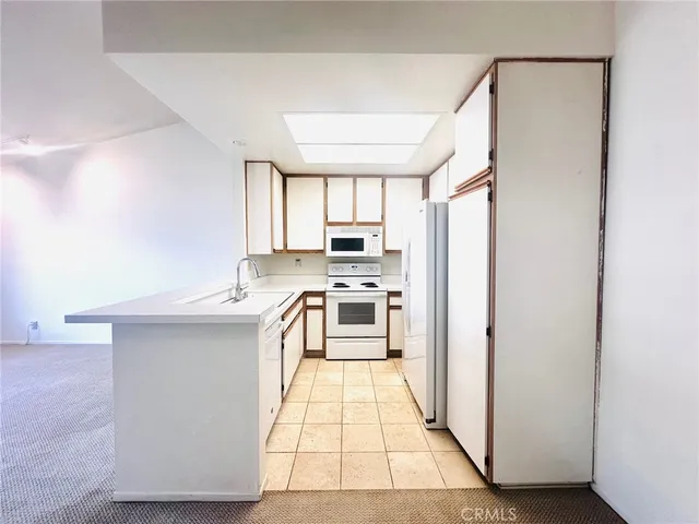 a kitchen with granite countertop a stove a sink and a refrigerator