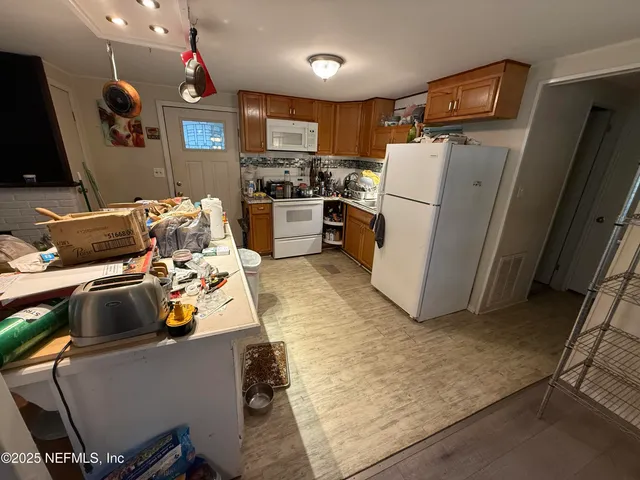 a view of a kitchen with fridge and workspace