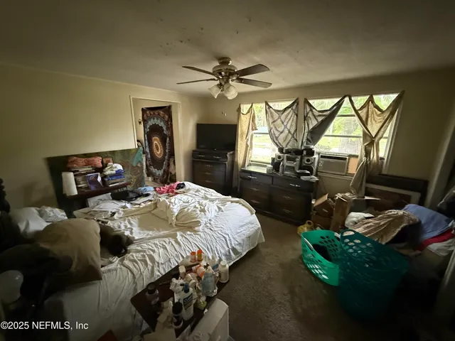 a bedroom with bed a flat tv screen and a dresser
