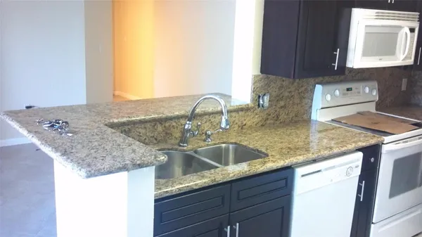 a kitchen with granite countertop a sink and a stove