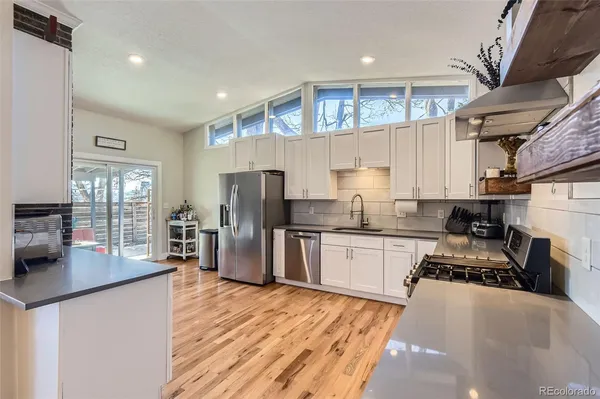 a kitchen with stainless steel appliances granite countertop a sink stove refrigerator and cabinets