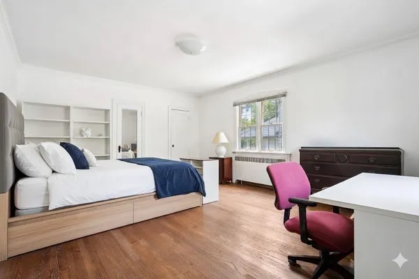 a bedroom with a bed a desk and chair with wooden floor