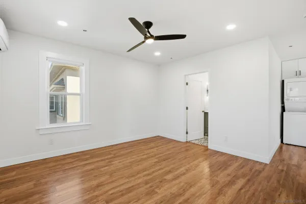 a view of an empty room with wooden floor and a window