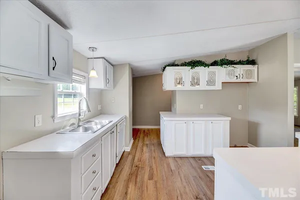 a kitchen with a sink a window and wooden floor