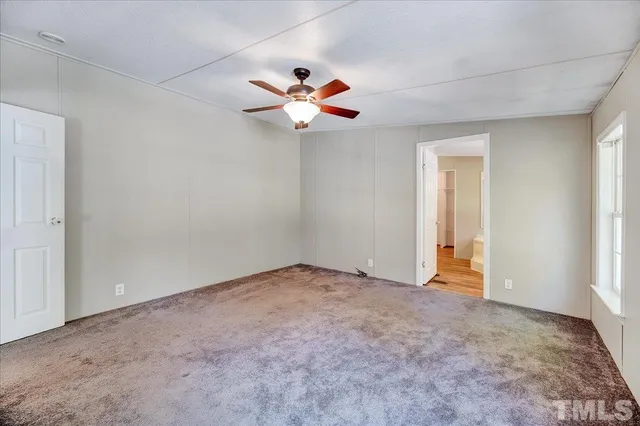 a view of a room with a ceiling fan and carpet
