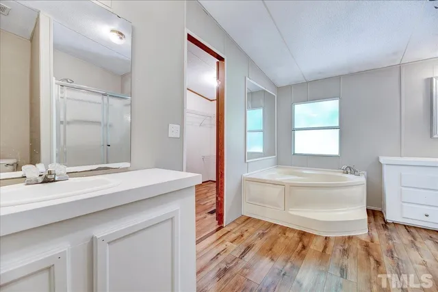 a spacious bathroom with a granite countertop sink toilet a large mirror and a bathtub