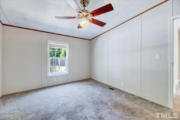 an empty room with windows and fan