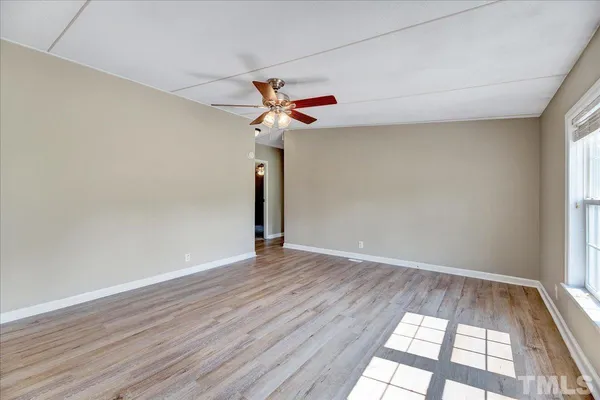 an empty room with wooden floor fan and windows