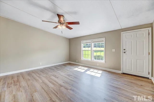 an empty room with wooden floor fan and windows