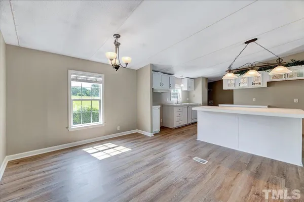 a view of a kitchen with wooden floor electronic appliances and window