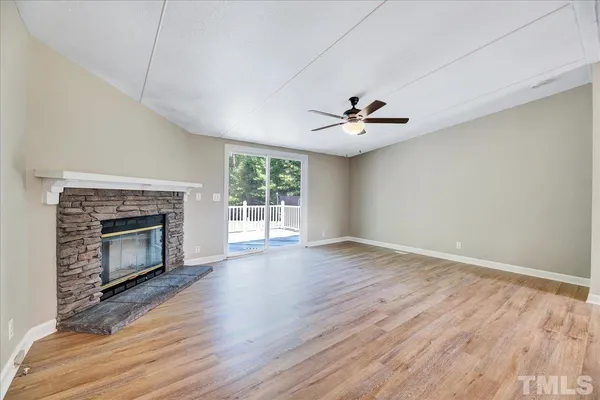 a view of a livingroom with a fireplace a ceiling fan and wooden floor